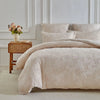 A beige duvet cover set with a delicate leaf print pattern displayed on a bed against a white wall.