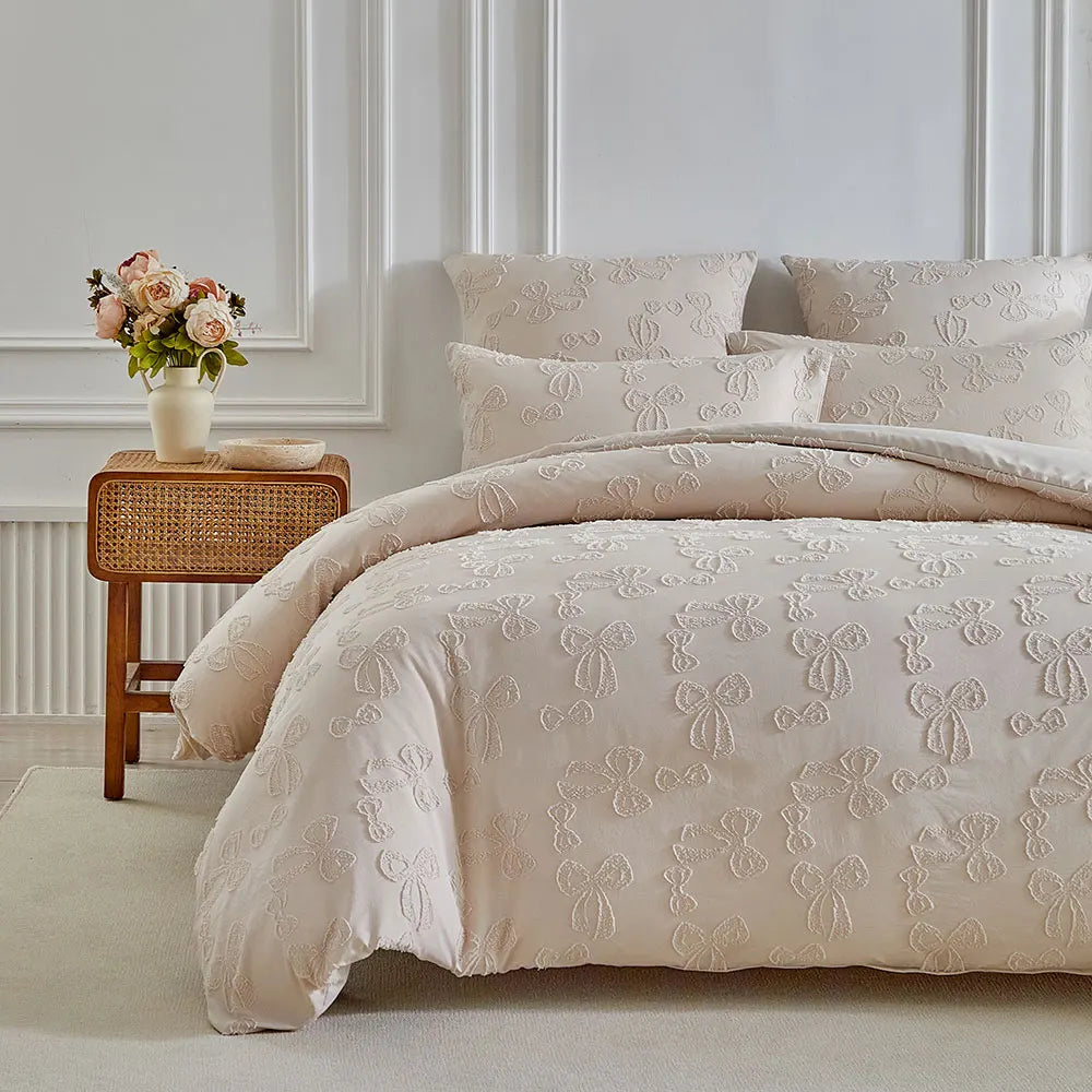 A beige duvet cover set with a delicate leaf print pattern displayed on a bed against a white wall.