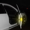 La puerta de un coche blanco está abierta, mostrando pegatinas reflectantes de seguridad en el marco de la puerta.