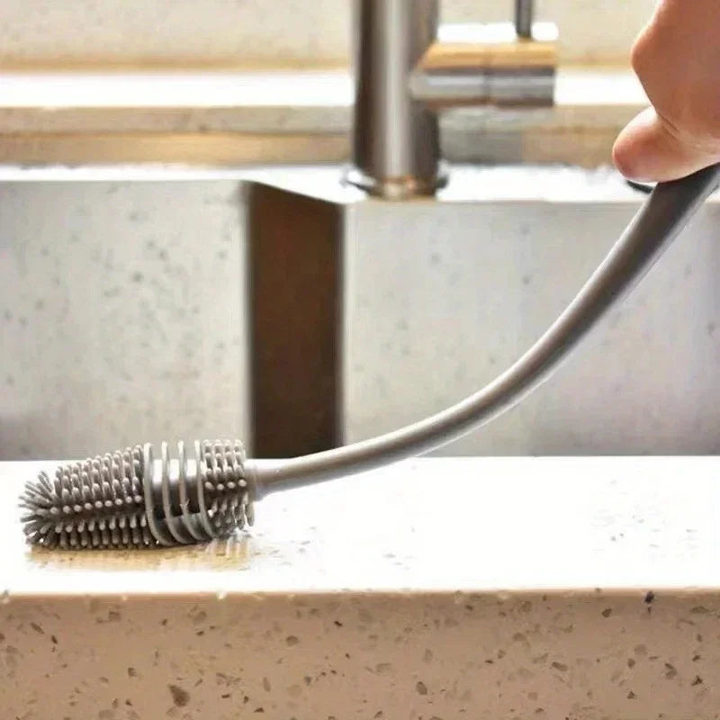 A silicone bottle brush with a long handle is shown cleaning a surface.