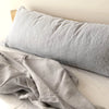 A light gray linen pillowcase is draped next to a folded gray linen fabric on a white surface.