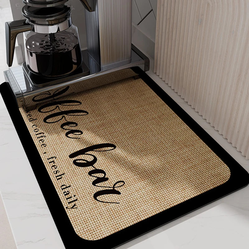 A black mat with the words 'Coffee Bar' embroidered in black script, placed under a coffee maker.