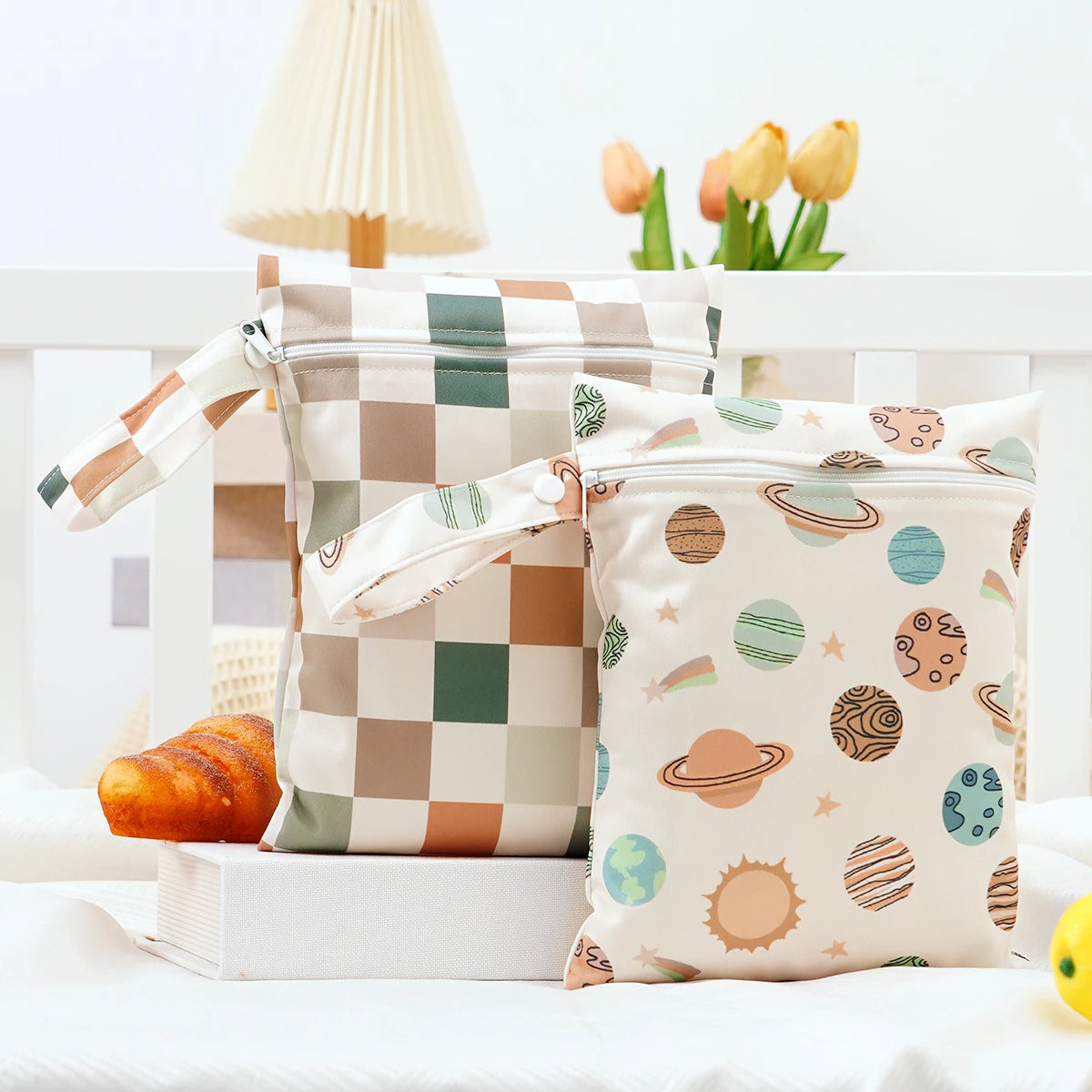 A pair of mini waterproof wet dry bags for baby in neutral tones and patterns resting on a white surface.