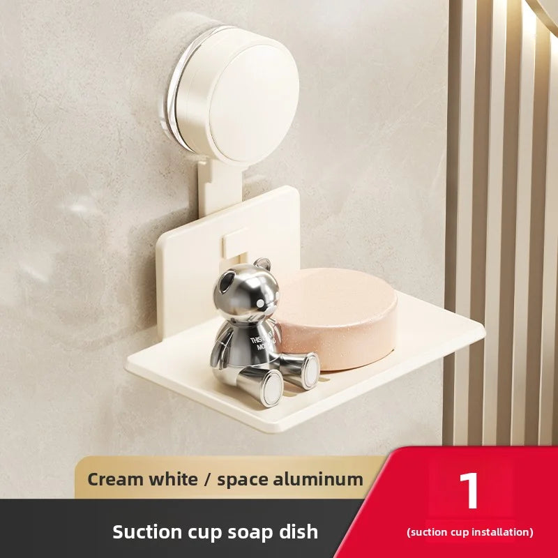 A cream white suction cup soap dish mounted on a wall, featuring a small bear design.