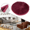 A deep burgundy shaggy round rug displayed in a living room setting with modern furniture.