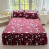 A deep magenta floral print bed skirt and pillowcase set with white flowers displayed on a bed.