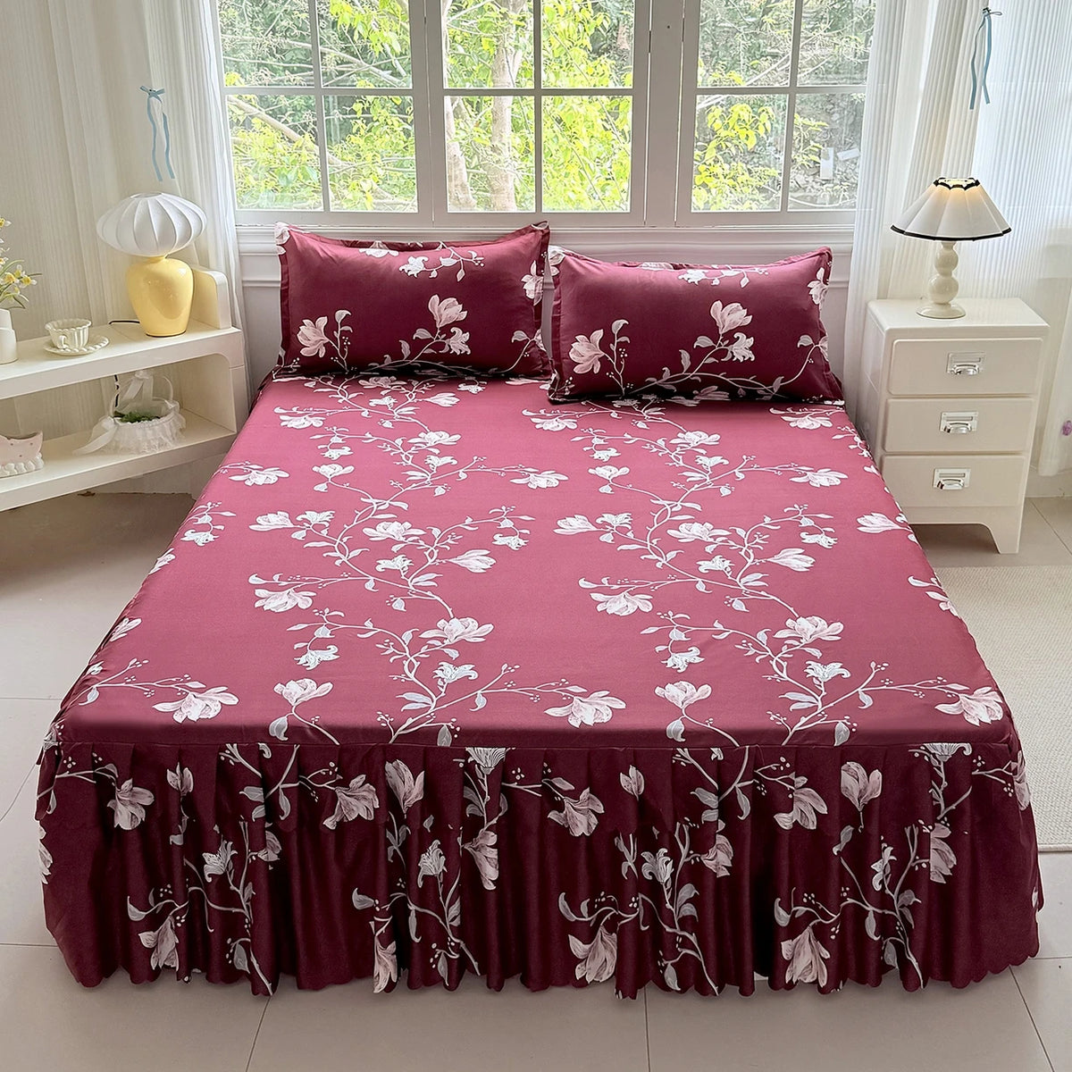 A deep magenta floral print bed skirt and pillowcase set with white flowers displayed on a bed.
