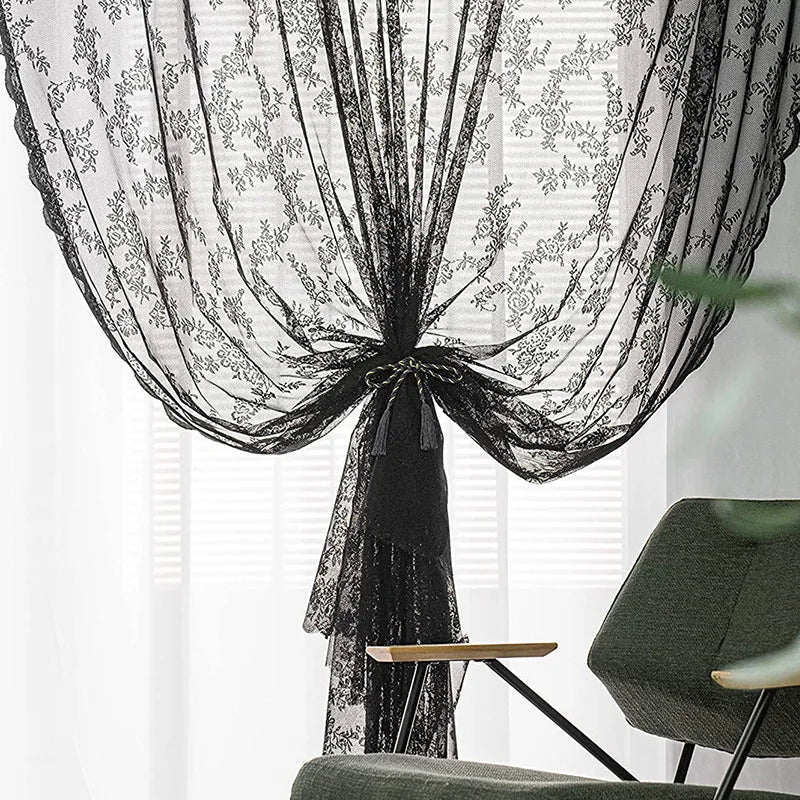 Rideaux de dentelle florale noire drapés élégamment dans une fenêtre.