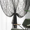Rideaux de dentelle florale noire drapés élégamment dans une fenêtre.