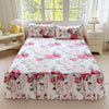 A white floral print bed skirt and pillowcase set displayed on a bed in a bright room.