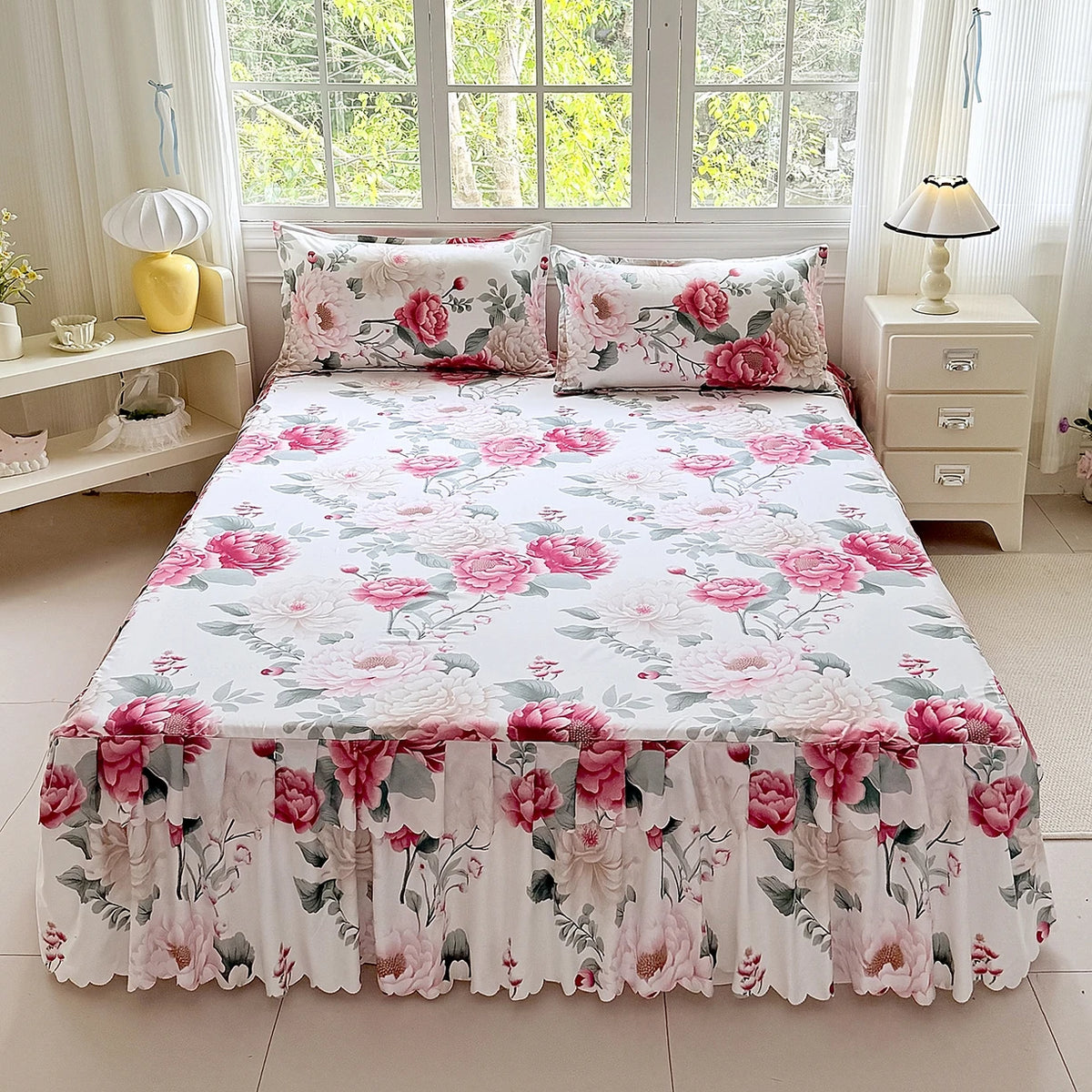 A white floral print bed skirt and pillowcase set displayed on a bed in a bright room.
