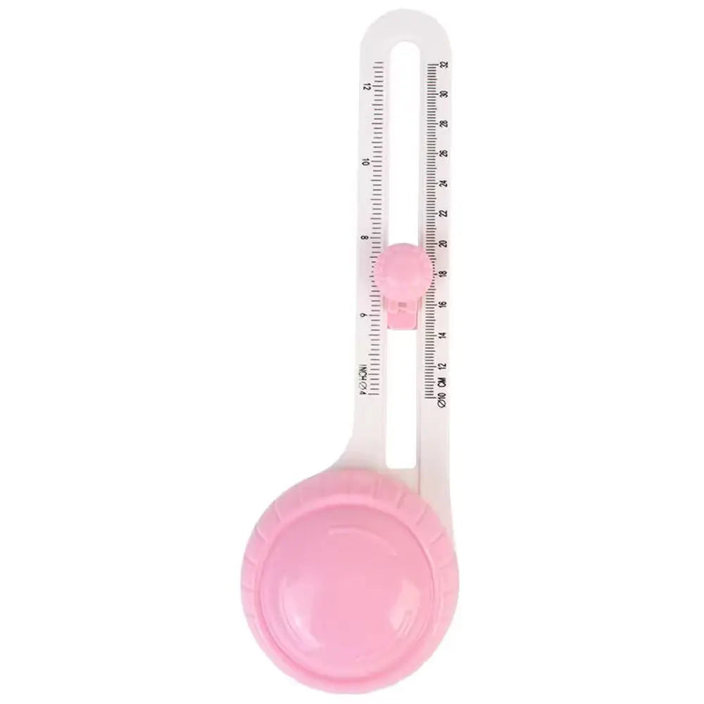 A pink adjustable circular paper cutter with a clear ruler and interchangeable blades.