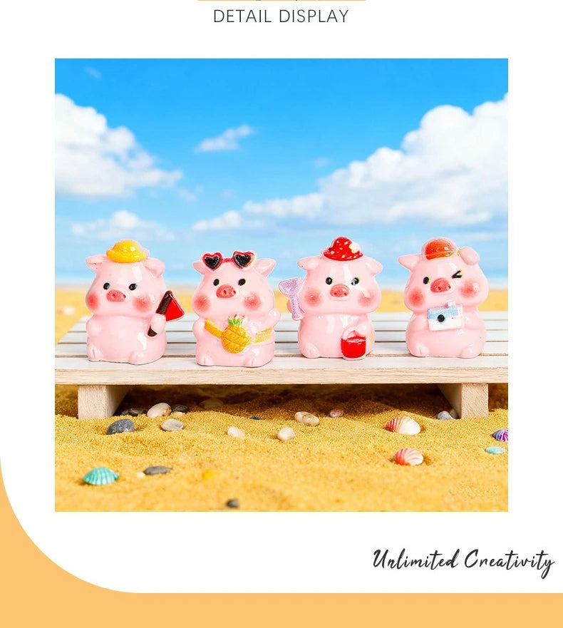 Four pink resin pig figurines with yellow and red accents displayed on a wooden surface amidst yellow sand.