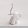 A white ceramic elephant and rabbit jewelry holder with a curved trunk and ears, used as a desk ornament.