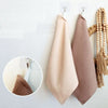 A set of four waffle weave towels in beige and taupe colors hanging on a white wall.