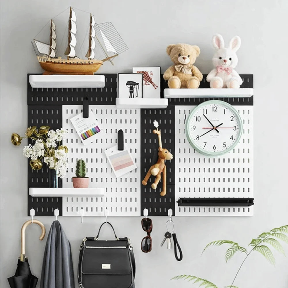 A black and white wall-mounted pegboard organizer with various hooks, storage boxes, and decorative items.