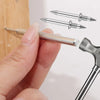A hand holds a double head wood nail kit showing a metal nail and a chisel tool.