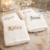 Three white embroidered face towels with names Kristin Jason and Kelsie resting on a marble surface