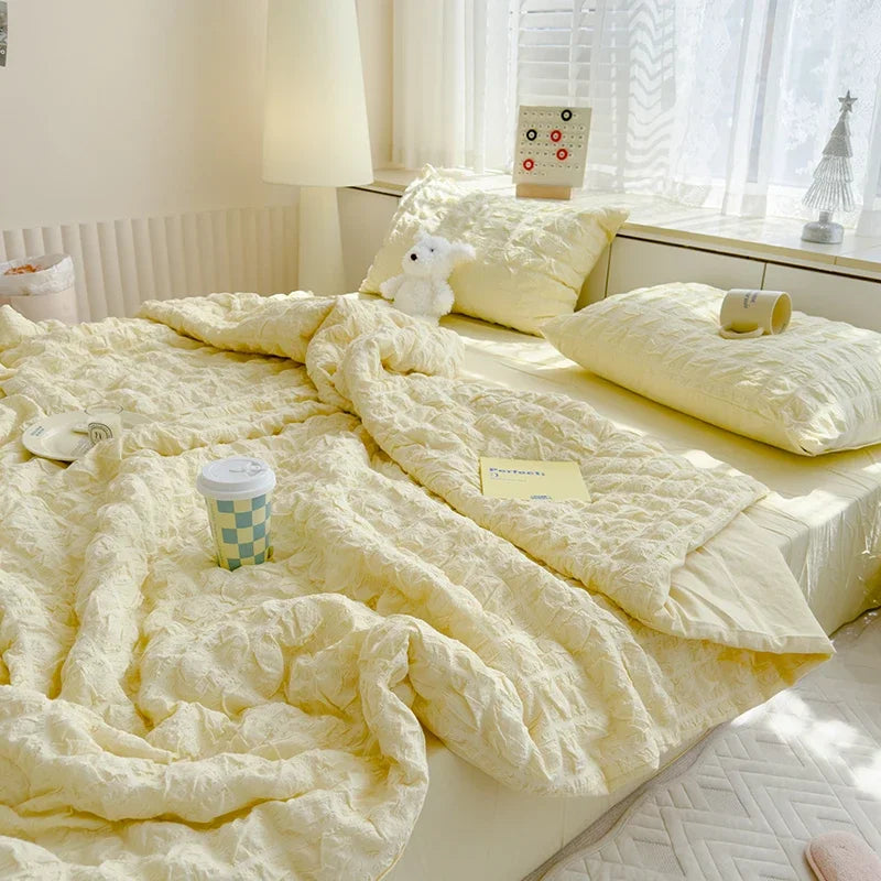 A fluffy yellow breathable summer seersucker quilt draped on a bed with white bedding and natural light.