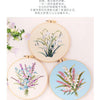 A set of three circular embroidery hoops displaying floral designs in soft blue and pink threads on white fabric.
