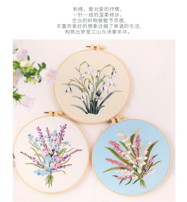 A set of three circular embroidery hoops displaying floral designs in soft blue and pink threads on white fabric.