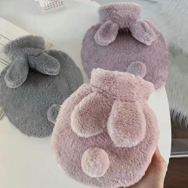 A hand holds a soft, pink plush rabbit hot water bottle with a fluffy flannel cover.