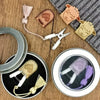 Precision mini scissors with protective leather covers and a purple thread