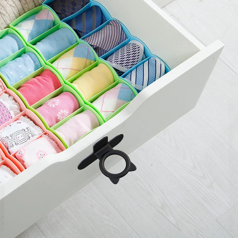 A white storage box filled with silicone toilet lids and lifters in various pastel colors and patterns.