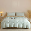 A light beige quilted duvet cover set with white pillowcases on a bed.