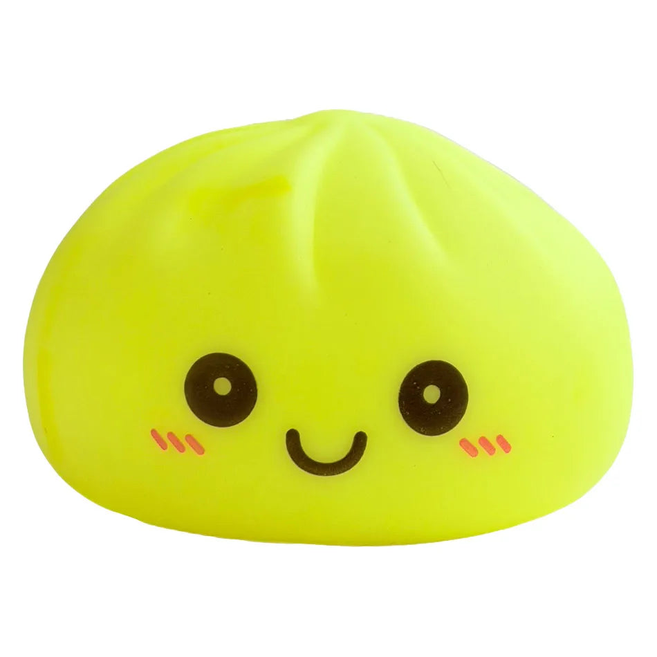 Un juguete amarillo brillante y suave en forma de dumpling sonriente con ojos negros y mejillas rosadas.