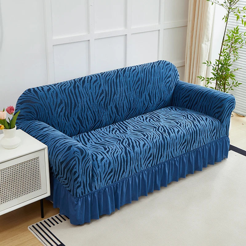 A deep blue jacquard sofa cover with a zebra stripe pattern and an elastic ruffle skirt displayed on a light-colored floor.