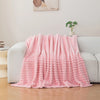A pink soft and cozy brushed flannel throw blanket draped over a white sofa.