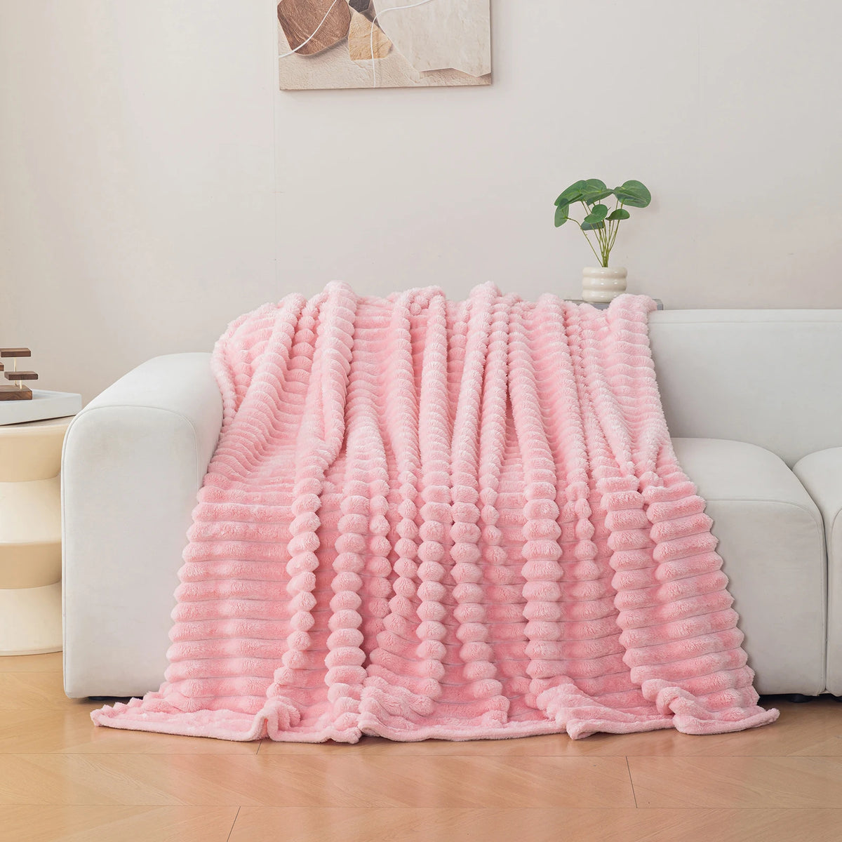 A pink soft and cozy brushed flannel throw blanket draped over a white sofa.