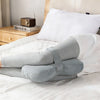Una almohada blanca y un par de almohadas de rodilla grises se exhiben en una cama con cabecero de madera.