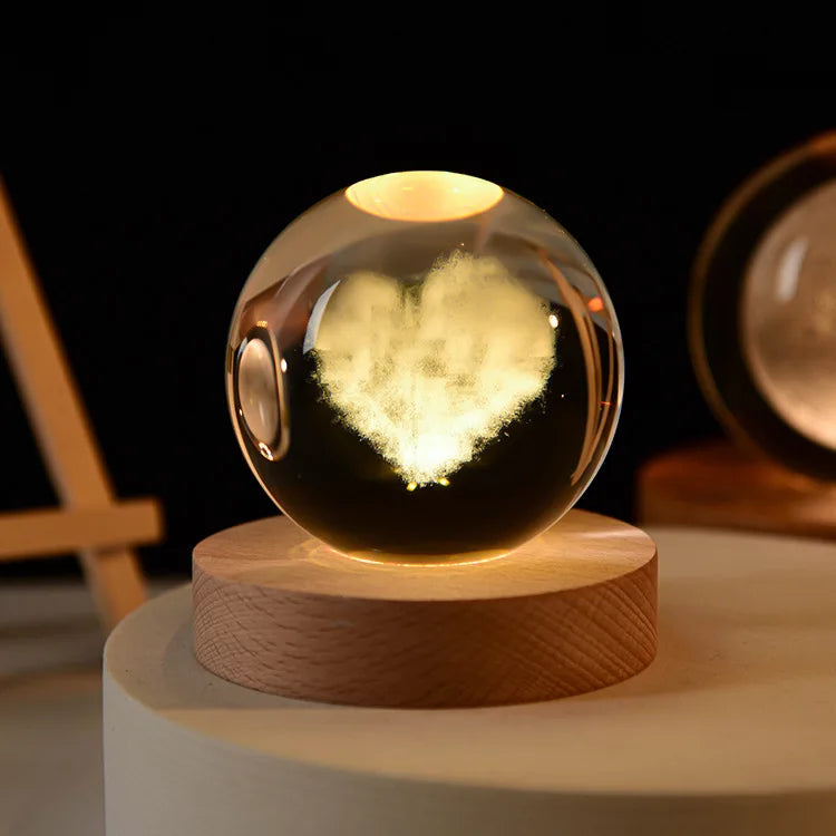 Laser engraved crystal ball night light with a glowing heart design on a wooden base