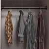 A row of hanging clothes displayed on a black tension rod with clips.