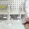 A clear acrylic photo and card display stand is held in a hand against a blurred background.
