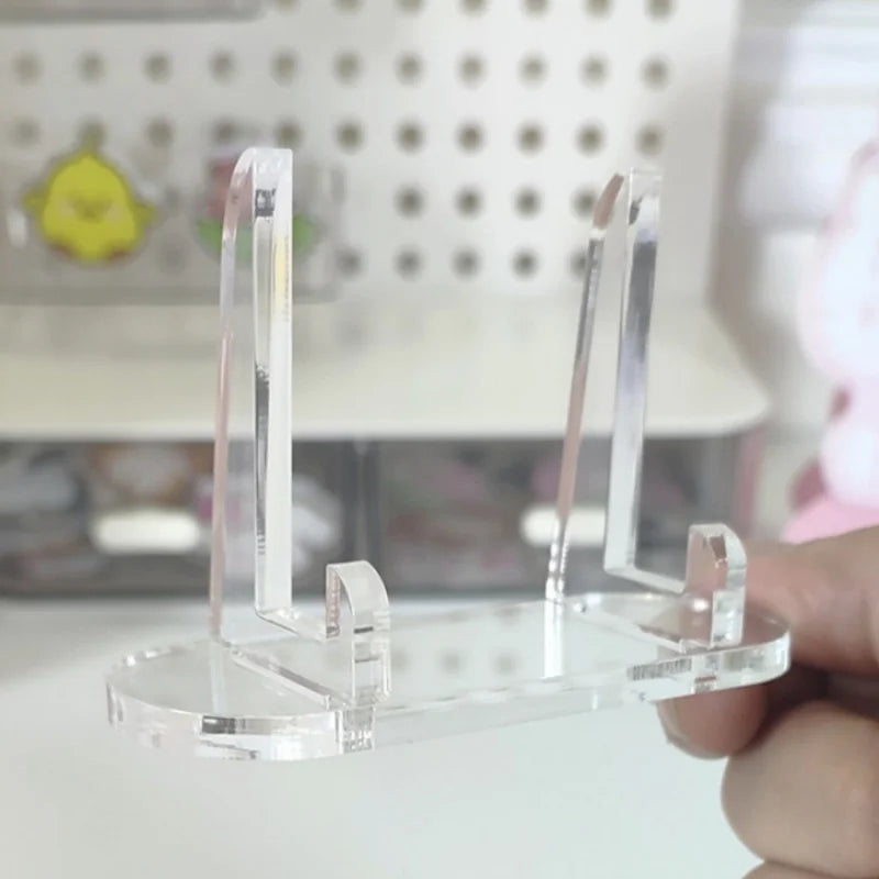 A clear acrylic photo and card display stand is held in a hand against a blurred background.