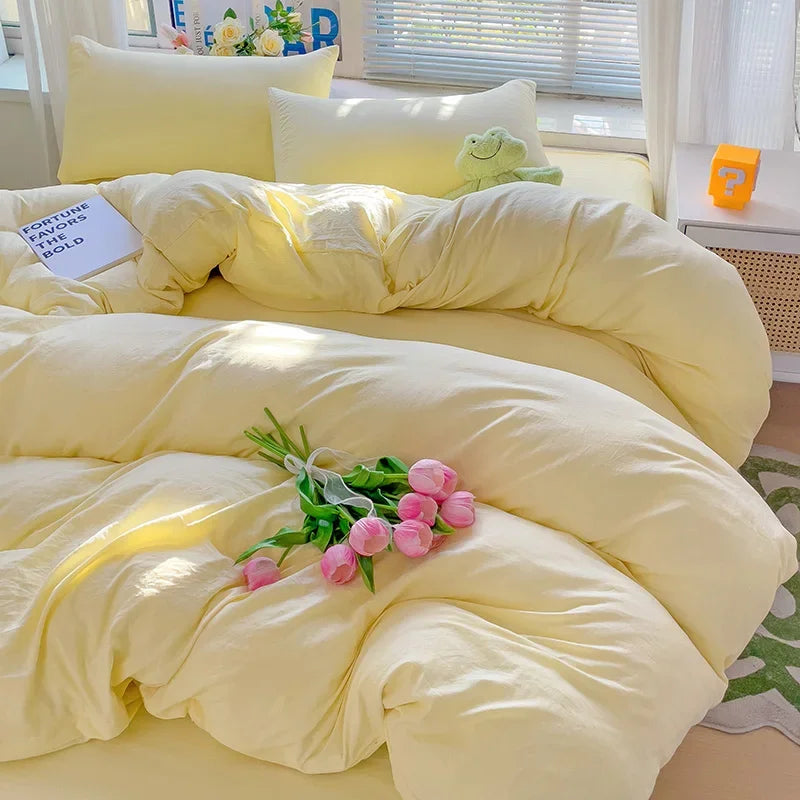 A yellow cotton bedding set featuring a flat sheet, duvet cover, and pillowcases with a light green accent.