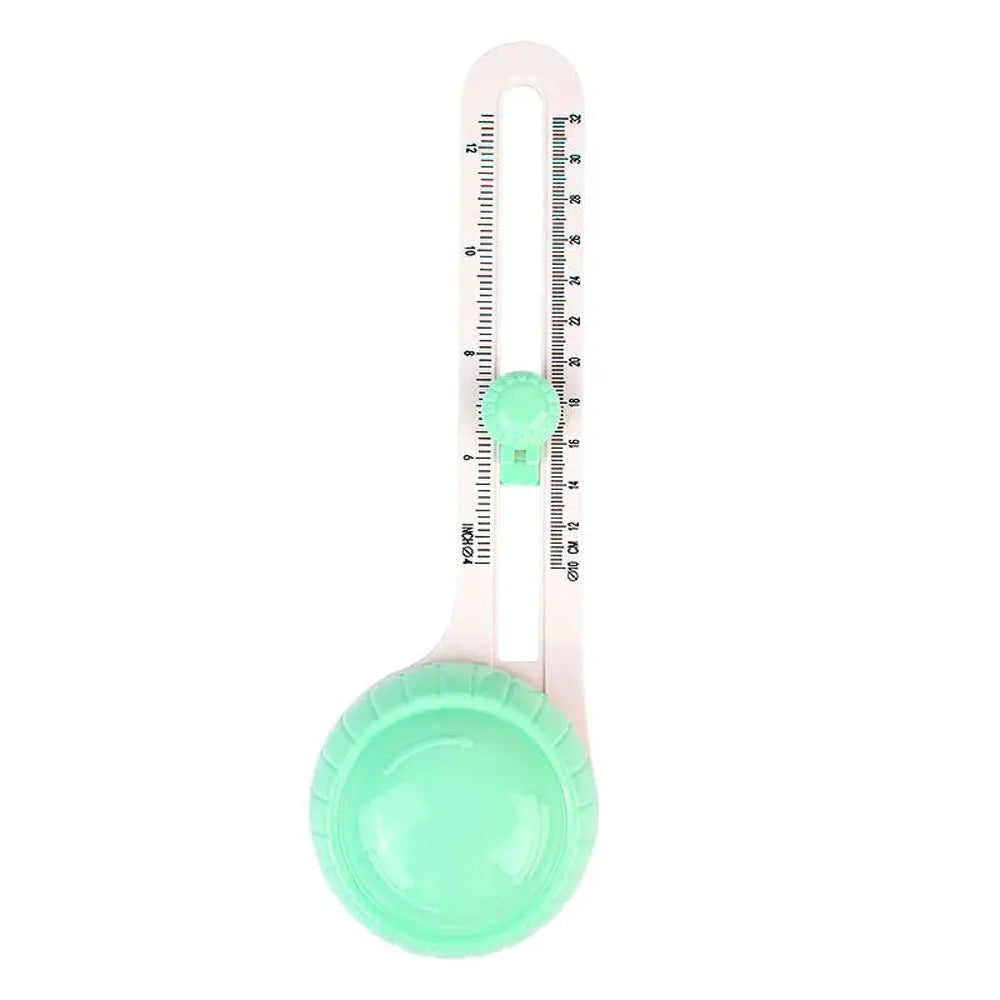 A pink adjustable circular paper cutter with a green blade and measurement markings.