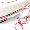 A hand is applying a flexible red PVC car bumper protection strip to a white car surface.