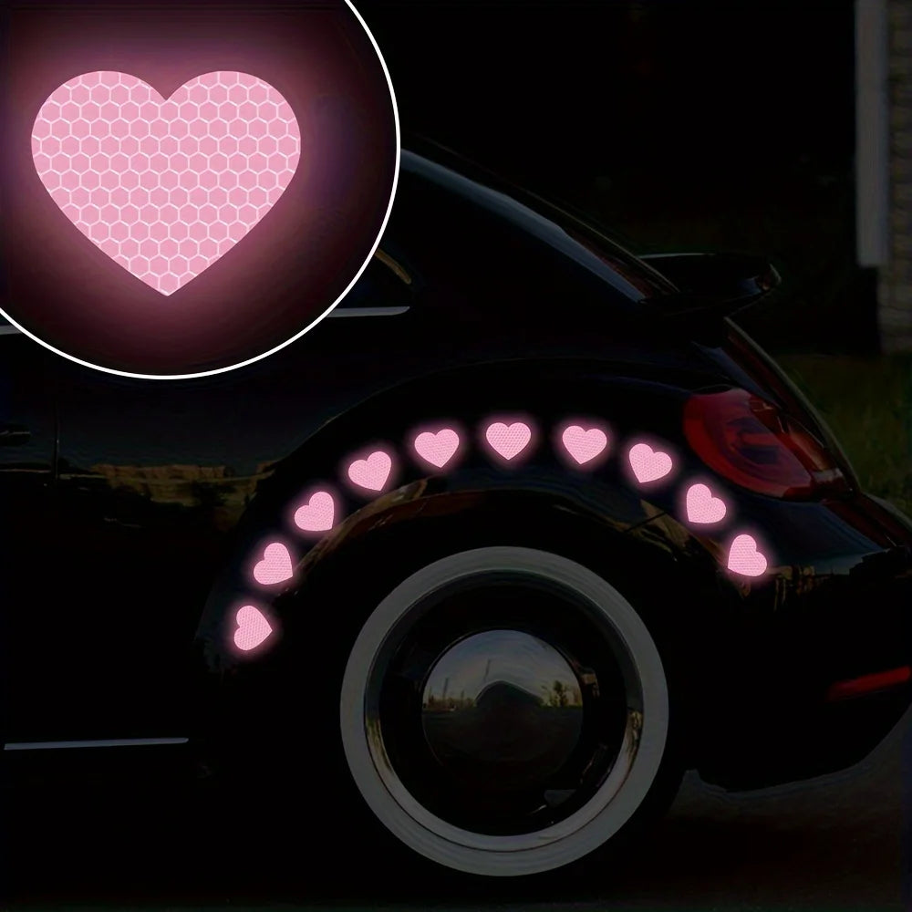 A black car features pink reflective heart stickers on the taillight and a heart-shaped decal.