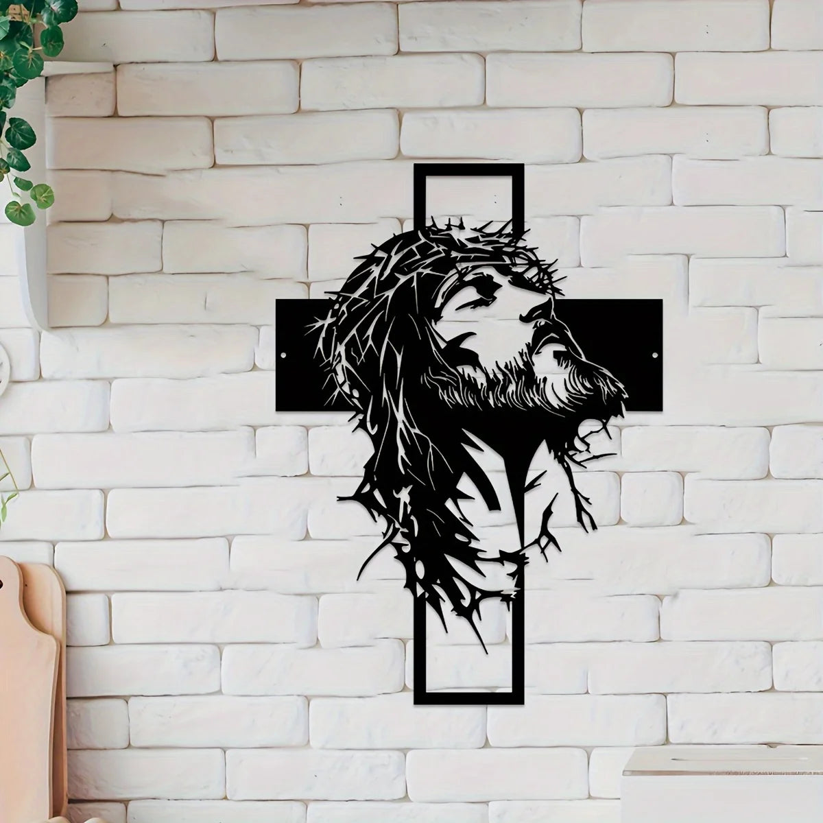 Silhouette de la tête et de la barbe de Jésus en métal noir avec un contour de croix sur un mur de briques blanches