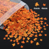 Orange and gold holographic star sequins scattered on a dark surface with size markers.
