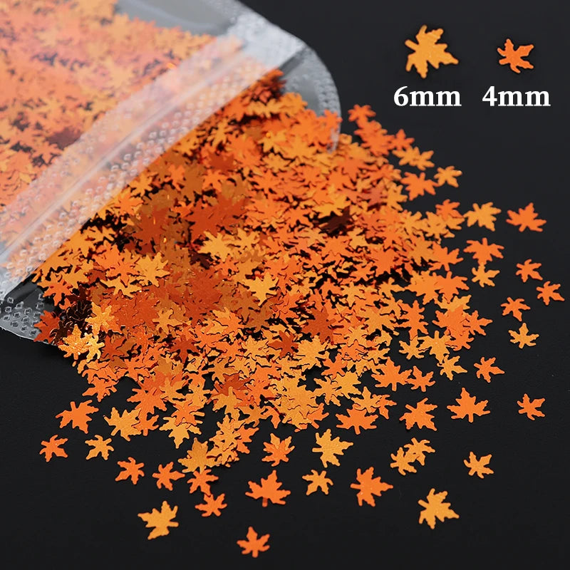Orange and gold holographic star sequins scattered on a dark surface with size markers.