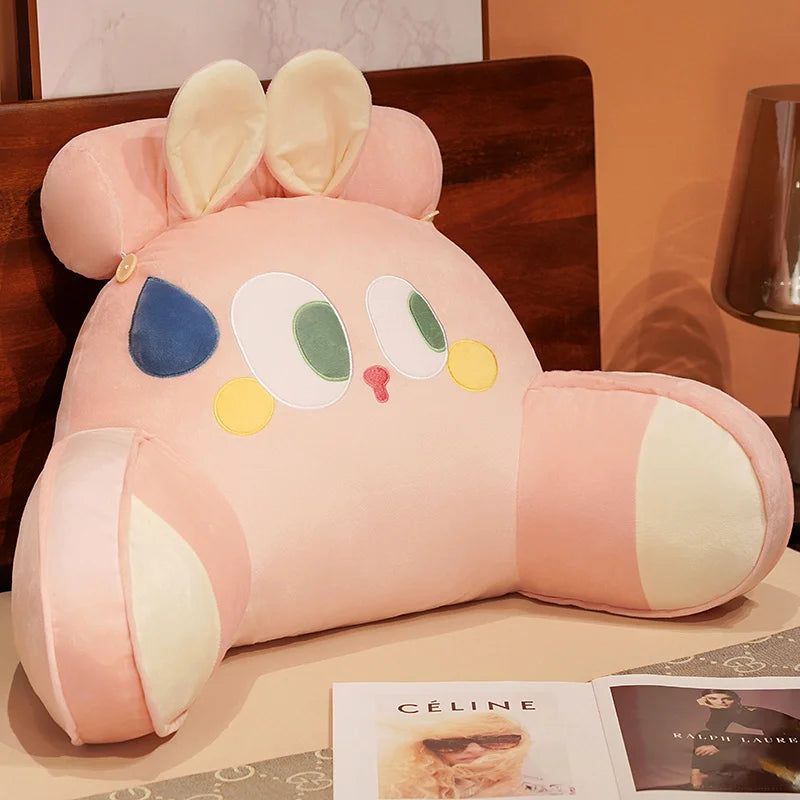A pink plush cat and dog backrest cushion resting on a wooden surface.