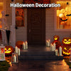 Halloween decoration featuring carved pumpkins, spooky silhouettes, and glowing pillar candles on a porch.