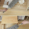 A hand is using a flexible microfiber duster to clean inside a wooden box or drawer.