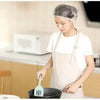 A woman wearing a disposable shower cap is preparing food with a fork in a pan.