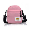 A pink Japanese style mini canvas crossbody bag with black strap and a white label.